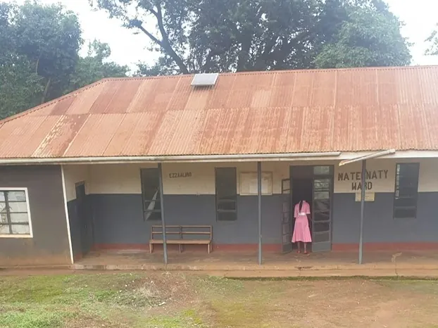 The old maternity ward at Kyebe: a single-storey building with a rusted iron roof and a hand-painted sign