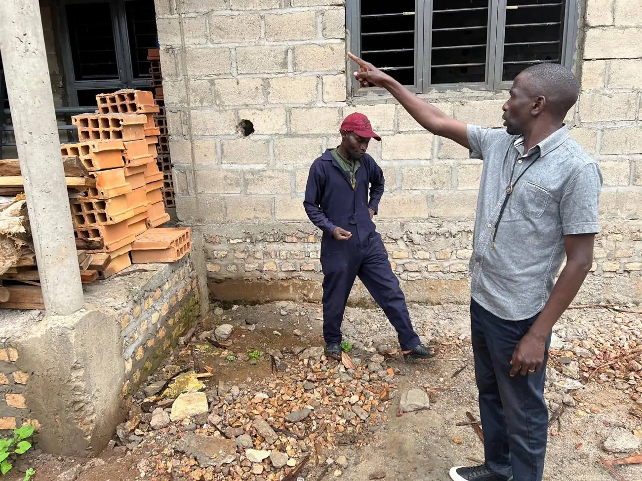 Two men discussing the construction work at Kyebe Health Centre III