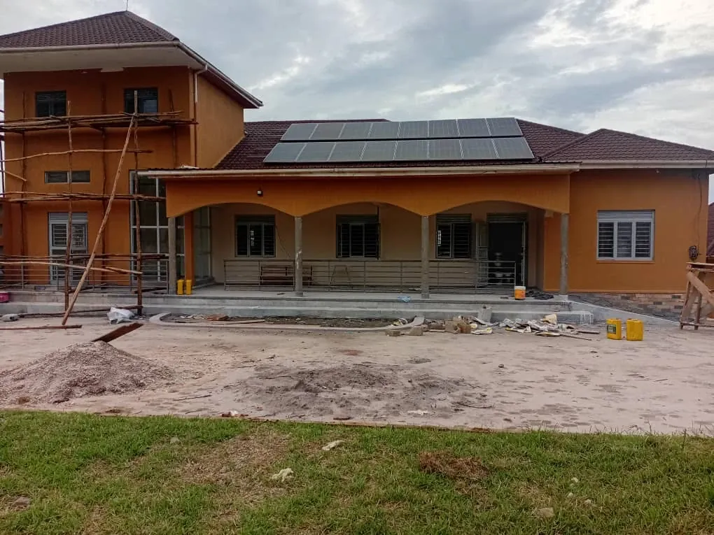 The new clinic nearly finished: an orange rendered building with a tiled roof and solar panels