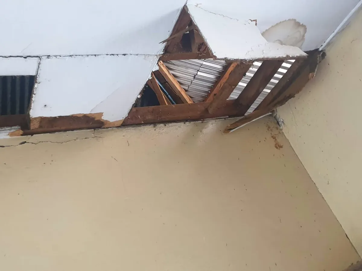 The ceiling in the old building, where the boards have fallen away and the roof beams show through